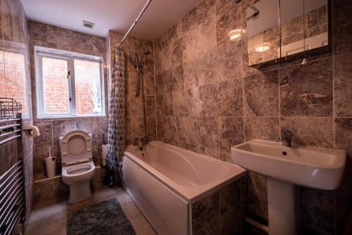 a bathroom with a sink and a tub and a toilet at Pristine Relocation 3-Bed House in London in London