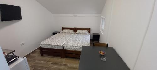 a small bedroom with a bed and a table at Apartmani Kovačević MKM Banja Vrujci in Gunjica