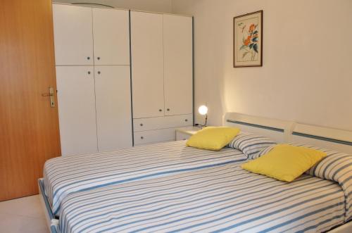 a bedroom with a bed with two yellow pillows at Appartamenti Rosanna in Grado