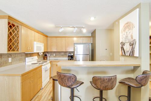 a kitchen with wooden cabinets and a island with bar stools at First-Floor Big Sky Condo with Hot Tub! in Big Sky