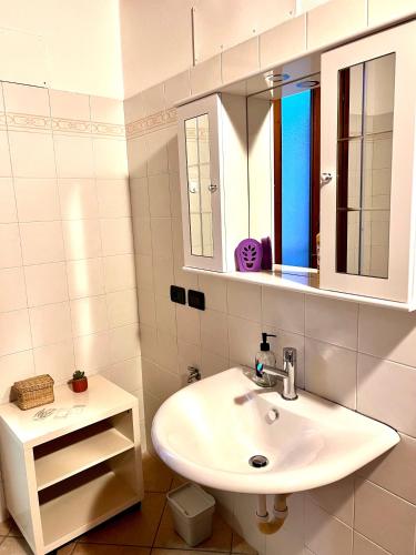W białej łazience znajduje się umywalka i lustro. w obiekcie Alloggi Mincio w mieście Goito