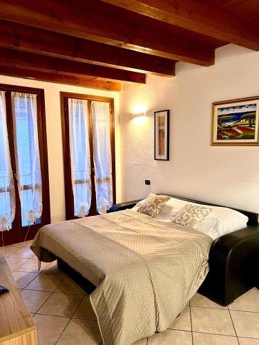 ein Schlafzimmer mit einem Bett in einem Zimmer mit Fenstern in der Unterkunft Alloggi Mincio in Goito