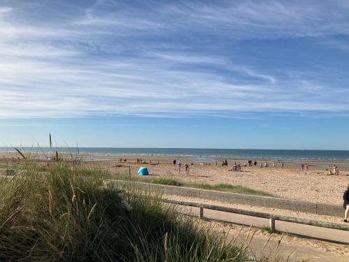 a group of people on a beach with the ocean at Appartement T.3 - Bord de mer in Ouistreham