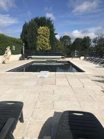 - une piscine dans un parc avec deux bancs dans l'établissement Gîte du Domaine de La Reine Blanche, à Criquetot-sur-Longueville