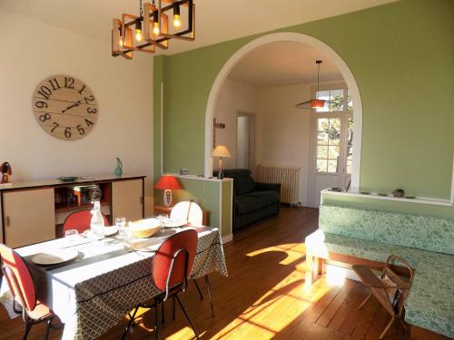 un salon avec une table avec des chaises et une horloge dans l'établissement Saint Georges de Didonne - MAISON CONFORTABLE au CALME - UNE PEPITE en VILLE, à Saint-Georges-de-Didonne