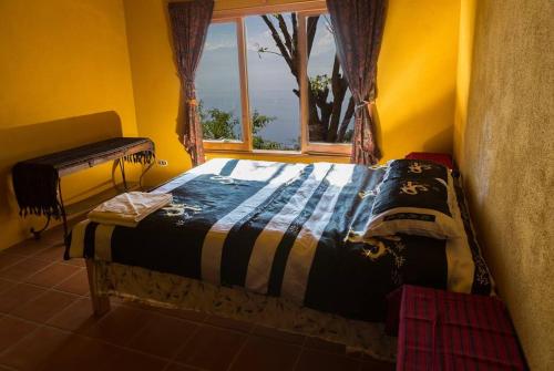 a bed in a yellow room with a window at Casa Maria Vista, Espectacular View in Santa Cruz La Laguna