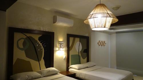 a bedroom with two beds and a chandelier at Hotel Boutique Kinich in Isla Mujeres