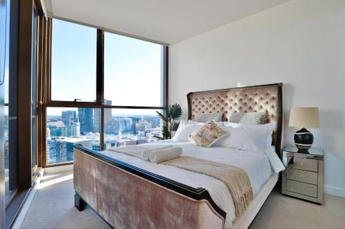 een slaapkamer met een groot bed en een groot raam bij Chic Zenith Retreat -Vista, Skylight, Parking in Sydney