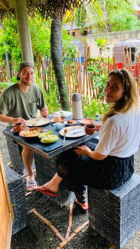 a man and a woman sitting at a table with food at Ayubowan Hiriketiya in Dickwella