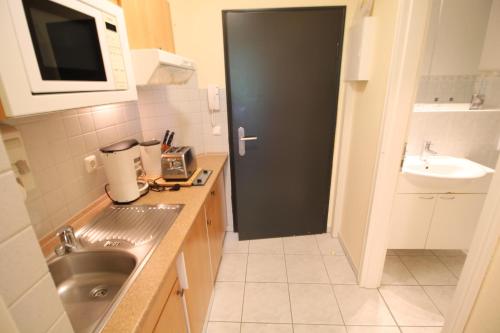 a small kitchen with a sink and a black door at Apartment zum See in Ascheberg