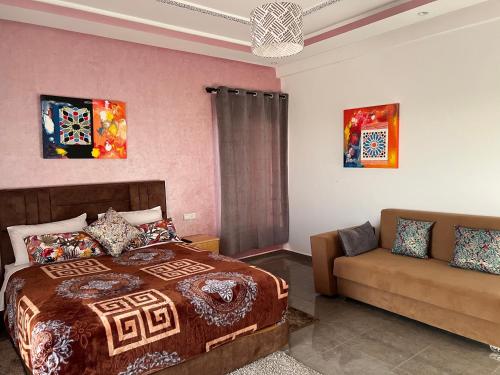 een slaapkamer met een bed en een bank bij Bidani Villa in Essaouira