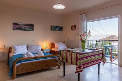 1 dormitorio con cama, mesa y balcón en MAKAROUNIS THEA II, en Petalidi