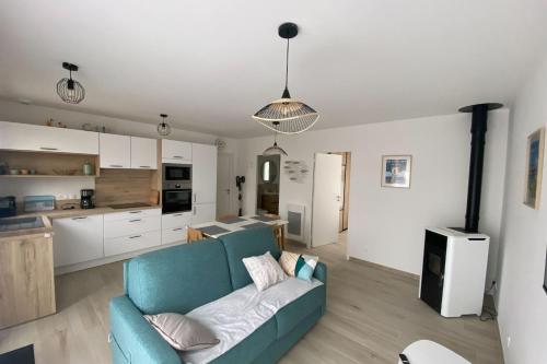 ein Wohnzimmer mit einem blauen Sofa und einer Küche in der Unterkunft New house on the seafront in Hermanville-sur-Mer