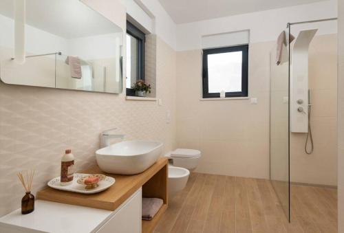 a white bathroom with a sink and a toilet at Villa Palm Bay 2, heated pool - 10 m from the sea in Ražanj