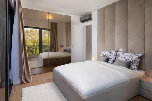 a bedroom with a large white bed and a mirror at Villa Palm Bay 2, heated pool - 10 m from the sea in Ražanj
