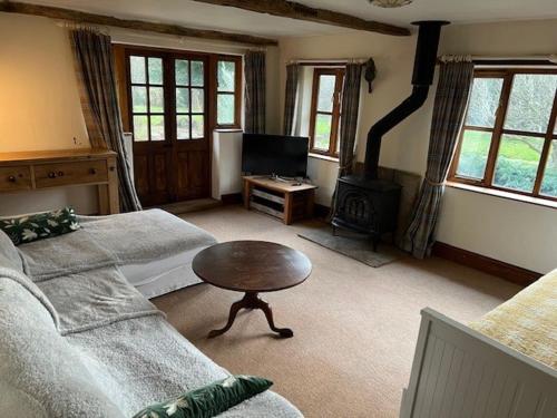 ein Wohnzimmer mit einem Sofa und einem Tisch in der Unterkunft Thatched Cottage in Ashford