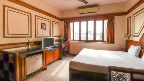 a bedroom with a bed and a desk with a computer at Bengal Chambers in Kolkata