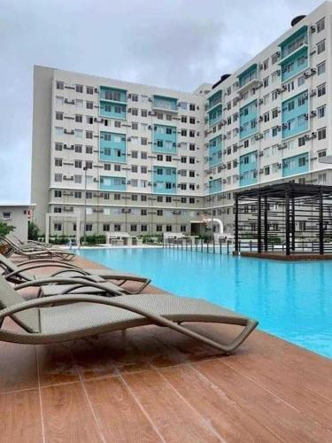 a large building with a swimming pool in front of it at Ezzel’s Place at Marina Spatial Dumaguete City in Dumaguete