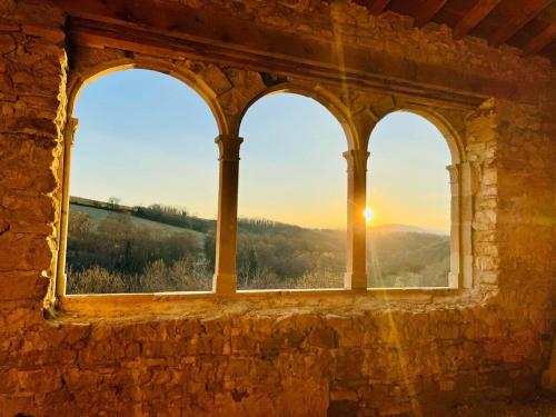 a window in a stone building looking out at the sunset at Le Logis d'Hortense in Vic-le-Comte