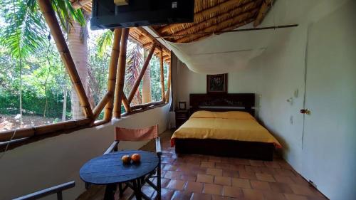 Schlafzimmer mit einem Bett, einem Tisch und einem Fenster in der Unterkunft Cabañas Coloniales con Entorno Natural en Barichara in Barichara