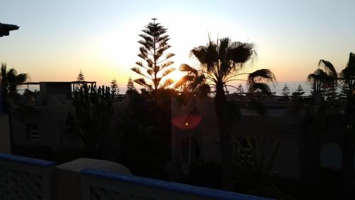 een zonsondergang vanaf een balkon met palmbomen en gebouwen bij Beach Villa in Tiznit