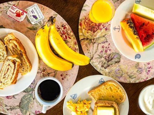 uma mesa com pratos de alimentos para o pequeno-almoço e uma chávena de café em VELINN Pousada dos Marinheiros em Ilhabela