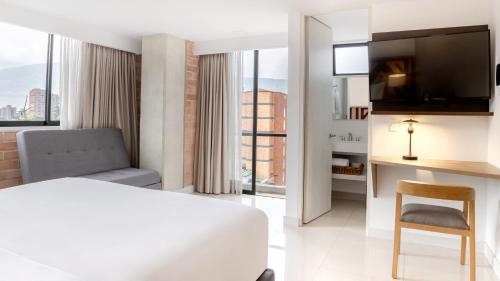 a hotel room with a bed and a desk with a chair at Origen Local Suites in Medellín