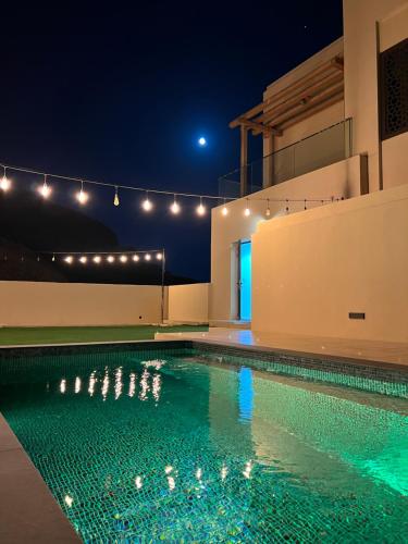a swimming pool at night with lights above it at W muscat bay in Muscat