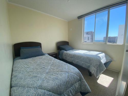 a bedroom with two beds and a window at Departamento a pasos de la playa y centros comerciales in La Serena