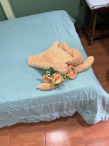a teddy bear laying on a bed with flowers at Ceiba lodge in Drake