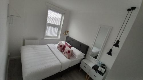 - une chambre avec un lit doté d'oreillers roses et d'un miroir dans l'établissement Home Away From Home, à Kent