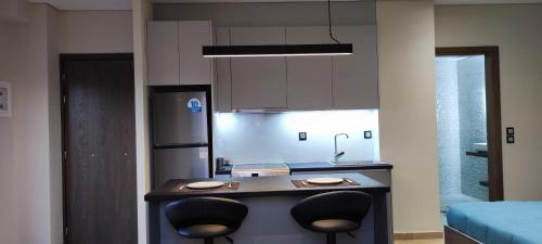 a kitchen with a counter with two chairs and a refrigerator at Superior Seaview Apartment in Antirrio