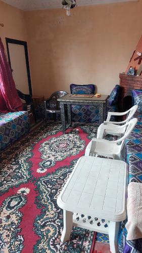 a room with three white chairs and a table and a rug at Maison d'hôtes grand atlas région Marrakech Ourika Asguine à 43 km de Marrakech in Ourika