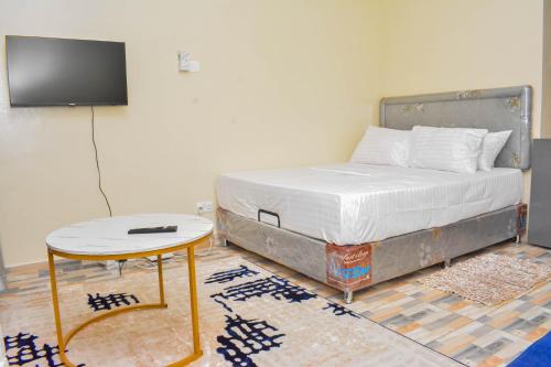 a bed in a room with a table and a tv at Evans' Cosy Studio Home in Mombasa