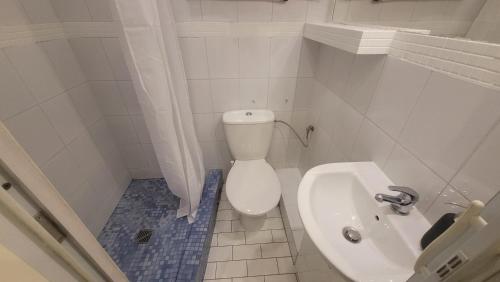 a white bathroom with a toilet and a sink at City Center Gdańska Apartment in Łódź
