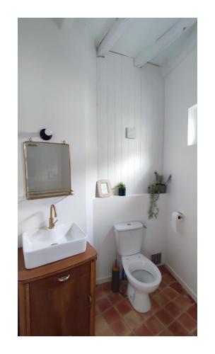 une salle de bain avec des toilettes blanches et un lavabo dans l'établissement Maison Charmeilles - Le studio Canon de Fronsac, à Fronsac