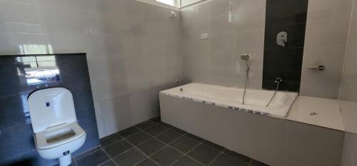 y baño con bañera, aseo y lavamanos. en Mazra Retreat, Coorg Kushālnagar, en Kushālnagar