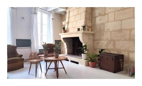 sala de estar con 2 mesas y chimenea en Maison Charmeilles - Le studio Canon de Fronsac en Fronsac