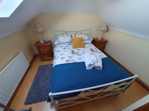 a bedroom with a bed with a blue comforter and two lamps at Quiet 2-Bedroom Buncrana Home in Buncrana