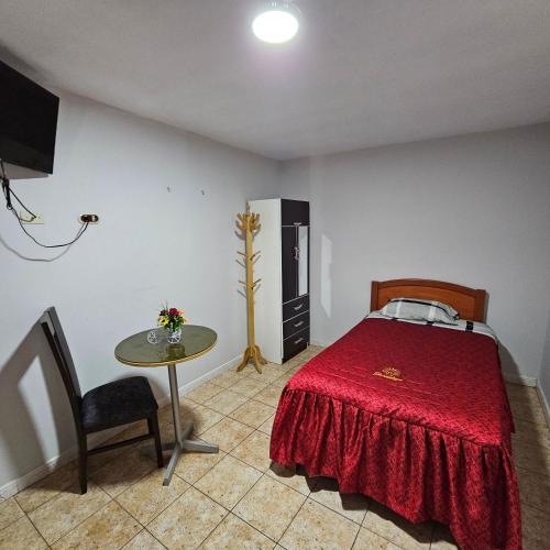 a bedroom with a red bed and a table at Hotel Guadalupe in Ilo