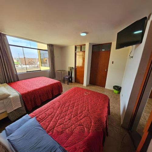 ein Hotelzimmer mit 2 Betten und einem Flachbild-TV in der Unterkunft Hotel Guadalupe in Ilo