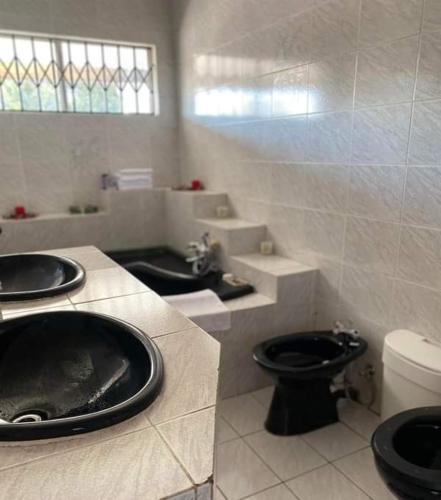 a bathroom with two sinks and a toilet at P&l exclusive beauty parlour in Johannesburg
