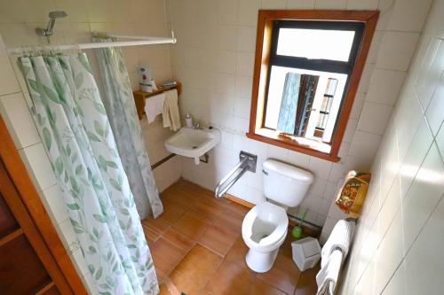 baño con aseo y lavabo y ventana en Punto Rockstar Osorno, en Osorno