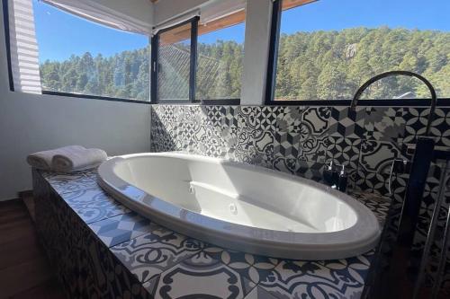 y baño con bañera y ventana grande. en Cabaña Alpina, en Creel