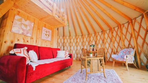 a living room with a red couch and two chairs at Glamping Niebiańska Osada Jurty Dolnośląskie in Wolany