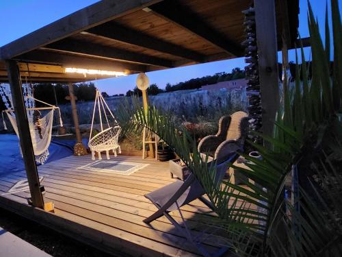 une terrasse en bois avec deux chaises et un hamac dans l'établissement Villa Saint Andrews, à Marly