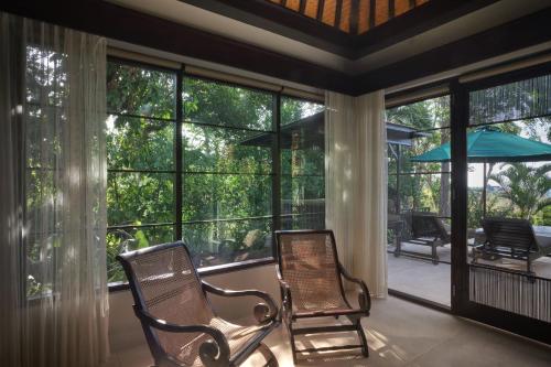 two chairs in a screened in porch with windows at The Damai in Lovina