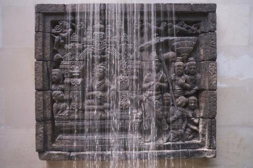 a stone wall with a water fountain at The Damai in Lovina