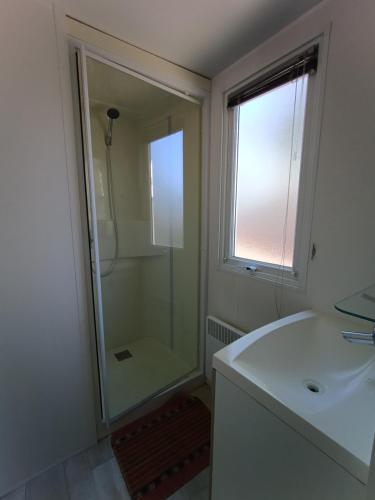 a bathroom with a shower and a white sink at camping 4 étoiles SIBLU Les sables du midi in Valras-Plage