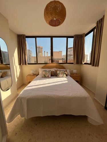 a bedroom with a large white bed with windows at Apartamento las OLAS playa de levante in Benidorm